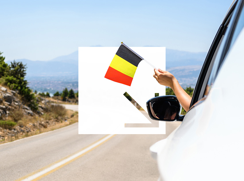Hand holding a Belgian flag out of a moving car, symbolising the need for car hire excess insurance when driving in Belgium.