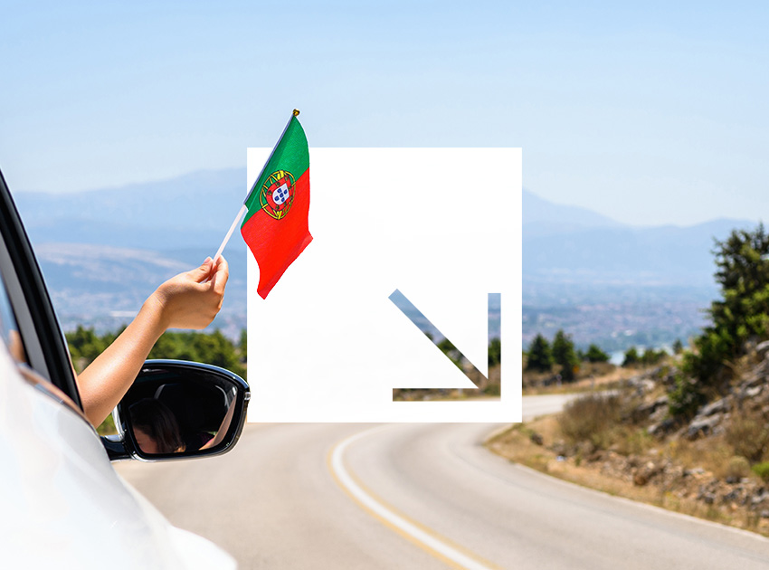 Hand waving a Portuguese flag from a car window on a rural road, representing safe travel supported by car hire excess insurance.