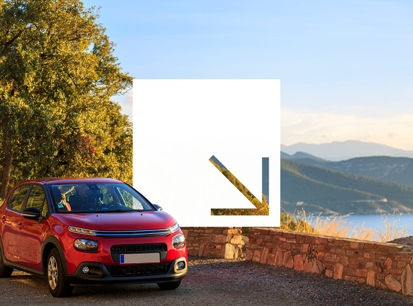 Red car parked against a scenic sunset landscape, ideal for road trips supported by car hire excess insurance.