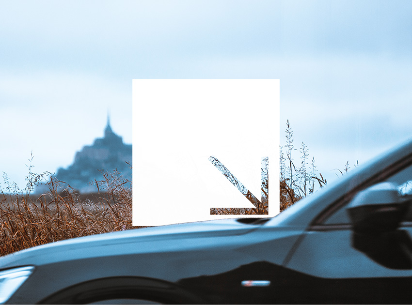 Car driving past fields with Mont-Saint-Michel in the background, useful for travellers exploring Normandy with car hire excess insurance.