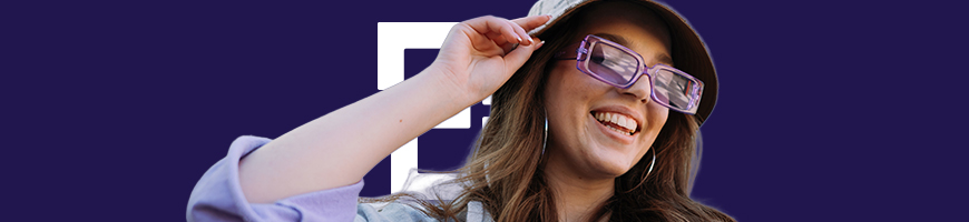 A person wearing a hat and large purple glasses smiles in front of a dark blue background with a white geometric shape.