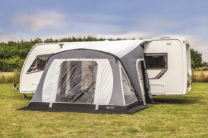 Sunncamp Swift 220 caravan awning attached to side of touring caravan parked in a green grassy field